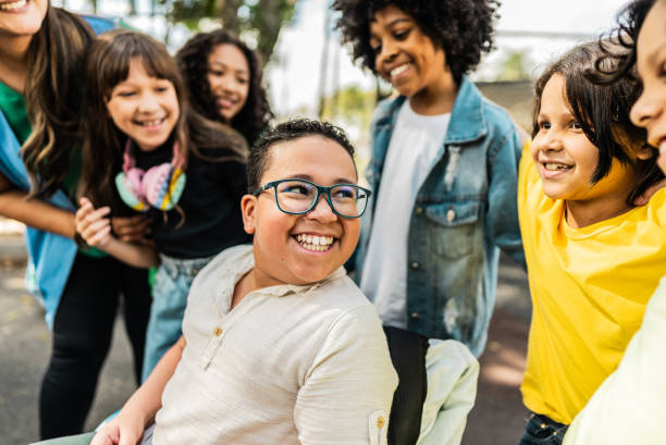 Happy students on schoolyard- including a wheelchair boy